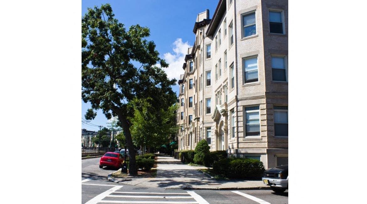 Four stroy apartment buildings on tree-lined street